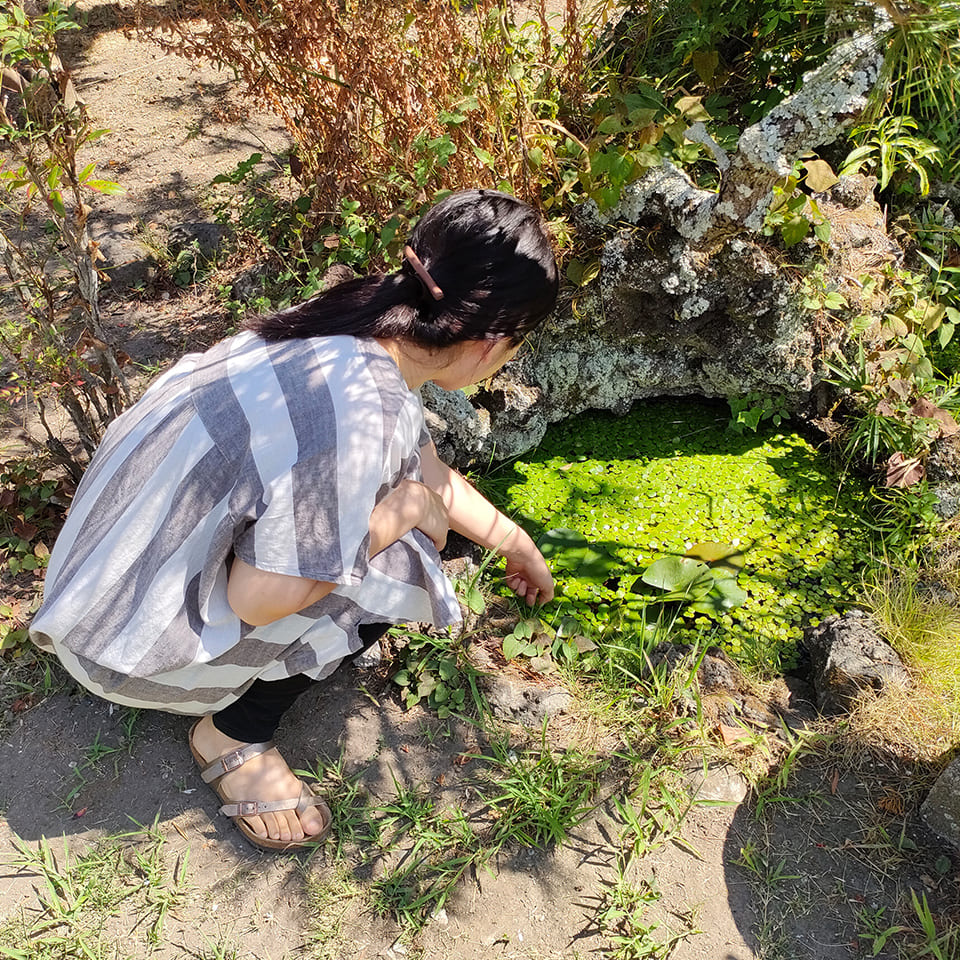 写真：小さな池を覗き込む micono さん